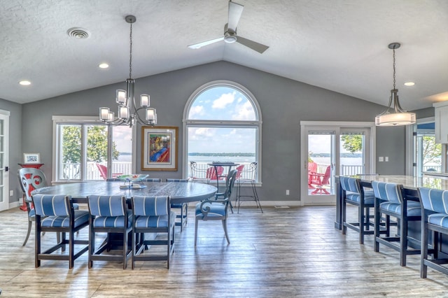 dining space featuring lofted ceiling, hardwood / wood-style floors, a textured ceiling, and ceiling fan with notable chandelier