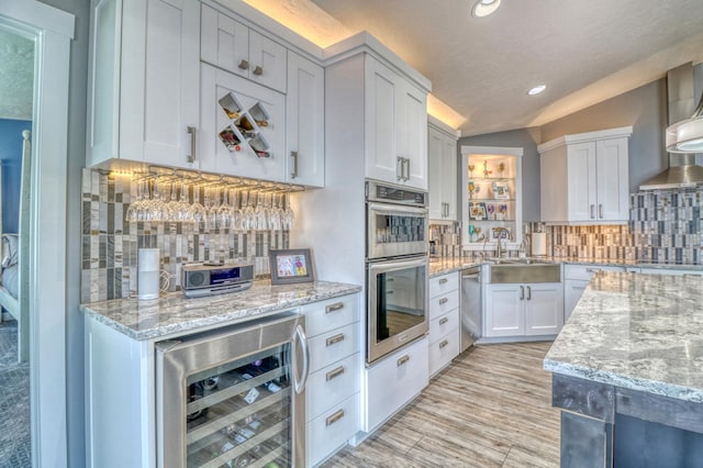 kitchen featuring backsplash, stainless steel appliances, vaulted ceiling, white cabinets, and wine cooler