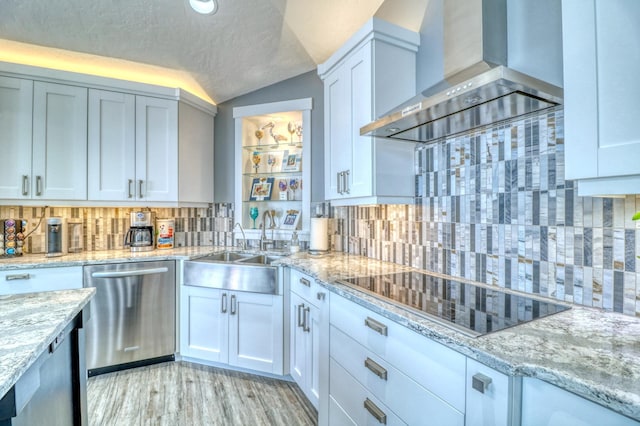 kitchen with wall chimney range hood, black electric cooktop, lofted ceiling, stainless steel dishwasher, and white cabinets