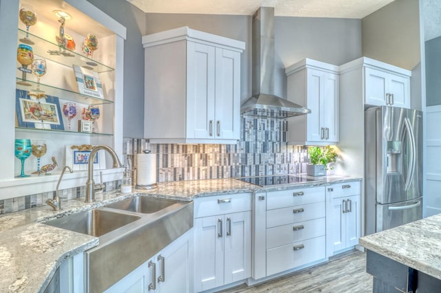 kitchen featuring wall chimney range hood, a textured ceiling, white cabinetry, lofted ceiling, and stainless steel fridge with ice dispenser