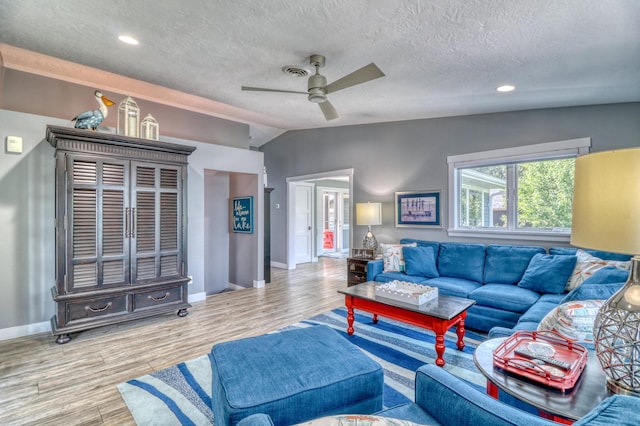 living room featuring light hardwood / wood-style flooring, a textured ceiling, vaulted ceiling, and ceiling fan