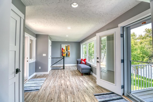 doorway with light hardwood / wood-style floors and a textured ceiling