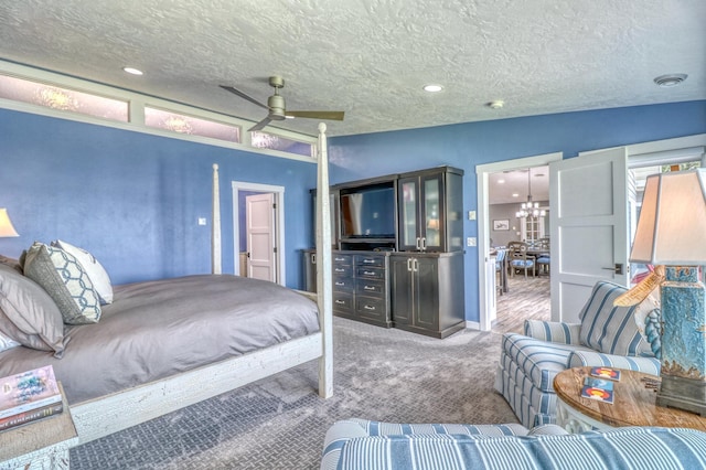 carpeted bedroom with a textured ceiling, vaulted ceiling, and ceiling fan with notable chandelier