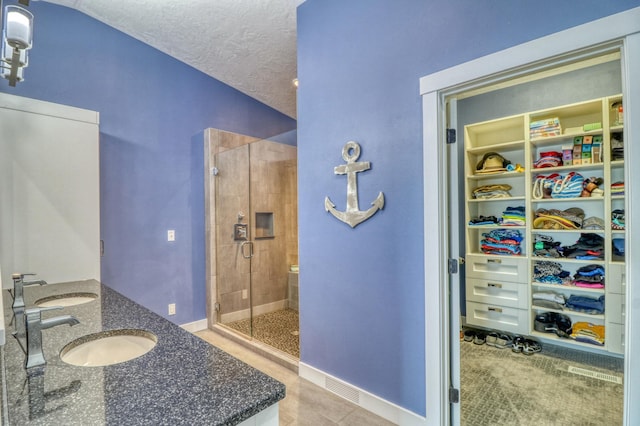 bathroom with a textured ceiling, vaulted ceiling, vanity, an enclosed shower, and tile patterned flooring