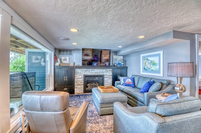 living room with a stone fireplace and a textured ceiling