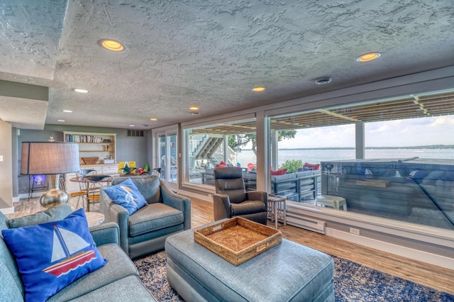 living room featuring hardwood / wood-style floors, a water view, and a textured ceiling