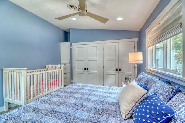 carpeted bedroom with lofted ceiling, a textured ceiling, a closet, and ceiling fan