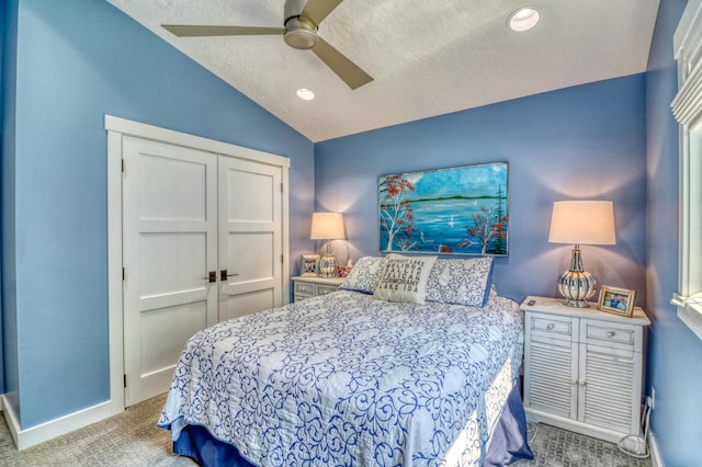 carpeted bedroom with lofted ceiling, a textured ceiling, a closet, and ceiling fan