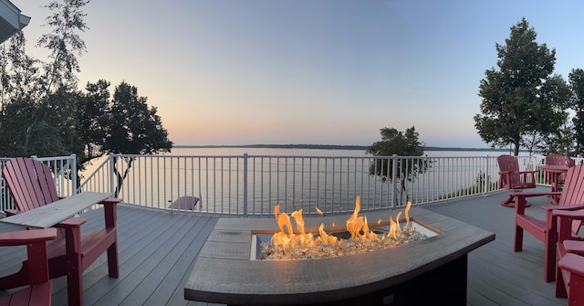 deck at dusk with an outdoor fire pit and a water view