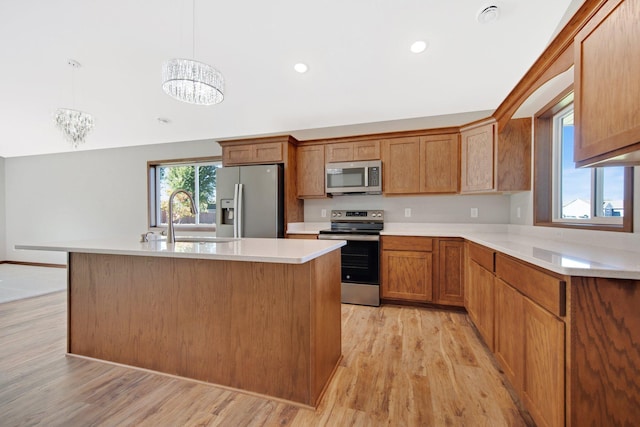 kitchen with sink, light wood-type flooring, stainless steel appliances, decorative light fixtures, and an inviting chandelier