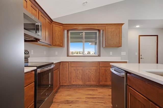 kitchen with light hardwood / wood-style floors, stainless steel appliances, and vaulted ceiling