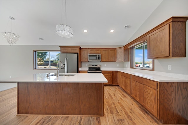 kitchen with lofted ceiling, appliances with stainless steel finishes, hanging light fixtures, and a healthy amount of sunlight