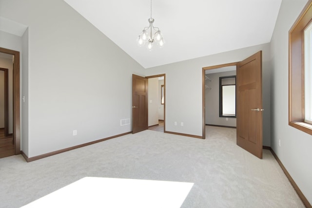 unfurnished bedroom featuring light carpet, a notable chandelier, and vaulted ceiling