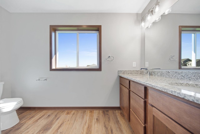 bathroom featuring vanity, toilet, wood-type flooring, and a wealth of natural light