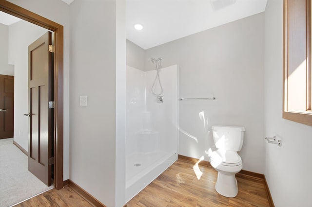 bathroom featuring toilet, hardwood / wood-style flooring, and a shower