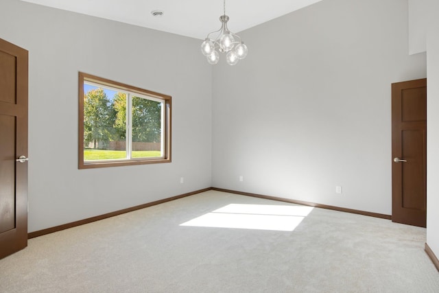 spare room featuring an inviting chandelier and light colored carpet