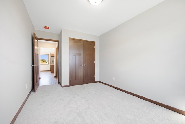 unfurnished bedroom with light carpet and a closet