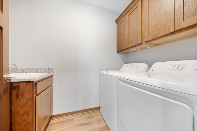 laundry room featuring sink, cabinets, light hardwood / wood-style flooring, and washing machine and clothes dryer