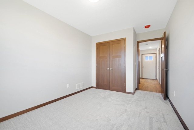 unfurnished bedroom with light carpet and a closet