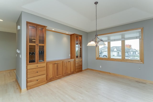 unfurnished dining area featuring a notable chandelier and light wood-type flooring