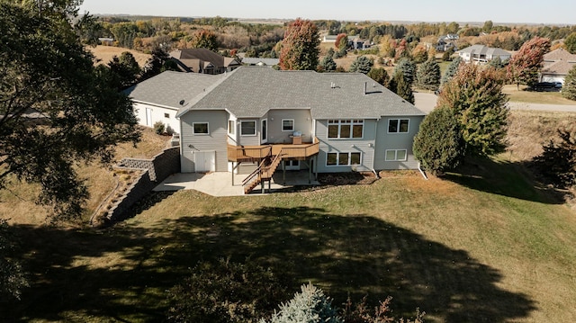 rear view of house with a wooden deck, a lawn, and a patio area