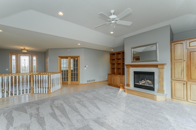 unfurnished living room with vaulted ceiling, light wood-type flooring, a fireplace, and french doors