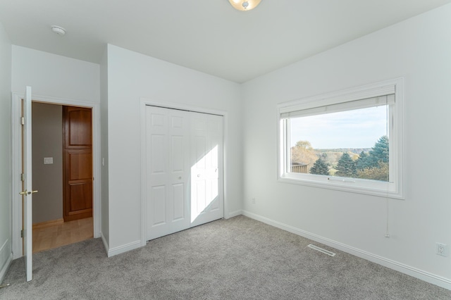 unfurnished bedroom with light colored carpet and a closet