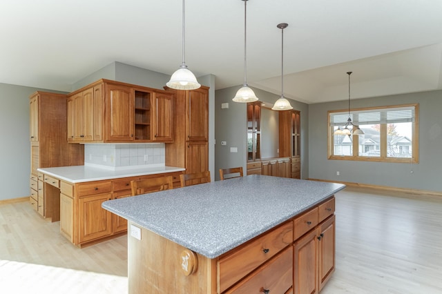 kitchen featuring tasteful backsplash, a kitchen island, pendant lighting, and light hardwood / wood-style floors