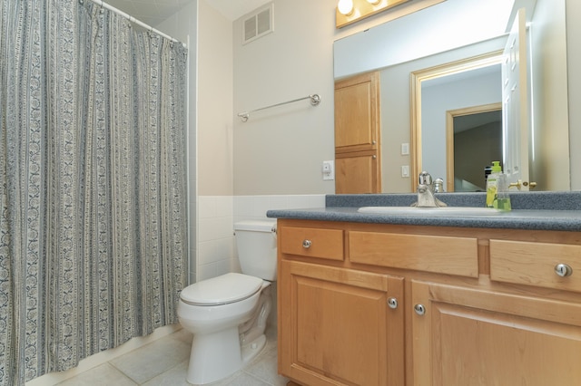 bathroom with tile patterned floors, toilet, vanity, and tile walls