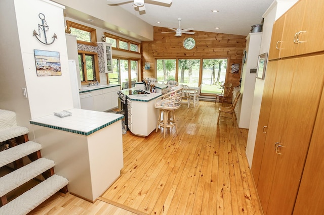 kitchen featuring lofted ceiling, a breakfast bar area, a center island, white cabinetry, and light hardwood / wood-style floors