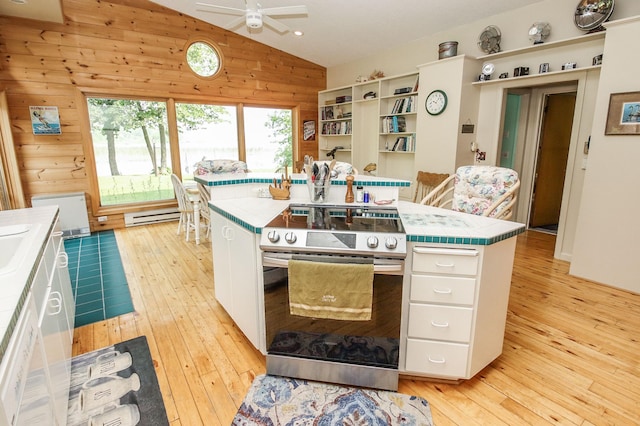 kitchen featuring an island with sink, electric stove, tile countertops, white cabinetry, and lofted ceiling