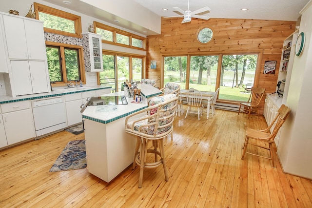 kitchen with dishwasher, a breakfast bar, wooden walls, and white cabinets