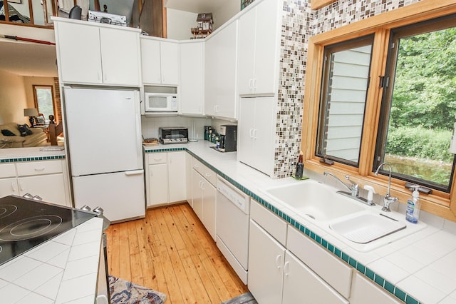 kitchen with white cabinetry, tile countertops, decorative backsplash, and white appliances