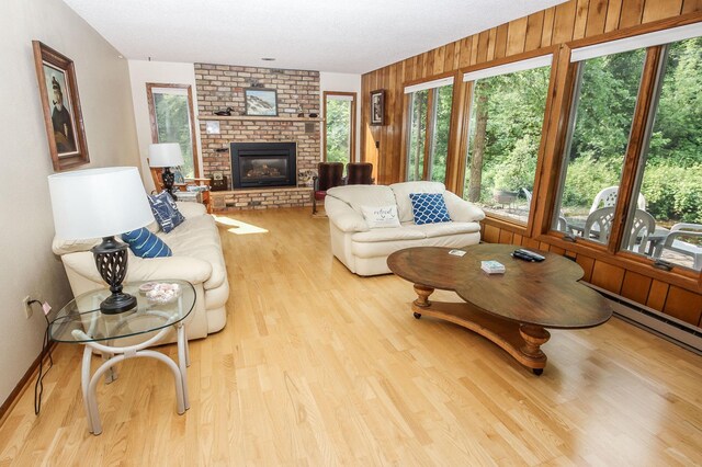 living room with wooden walls, a fireplace, and light wood-type flooring