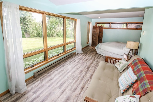 bedroom with light hardwood / wood-style floors and baseboard heating