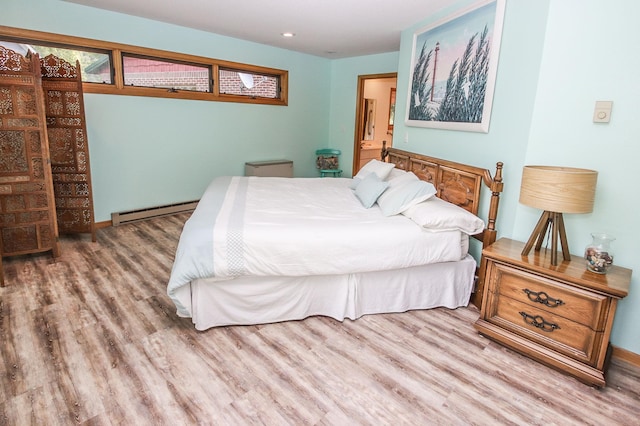 bedroom featuring a baseboard heating unit and hardwood / wood-style flooring