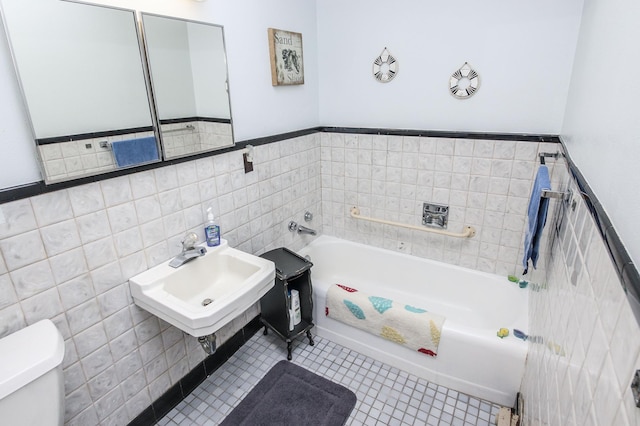 bathroom with tile walls, sink, a bath, and toilet