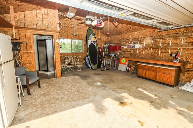 garage featuring a garage door opener, white fridge, and ceiling fan