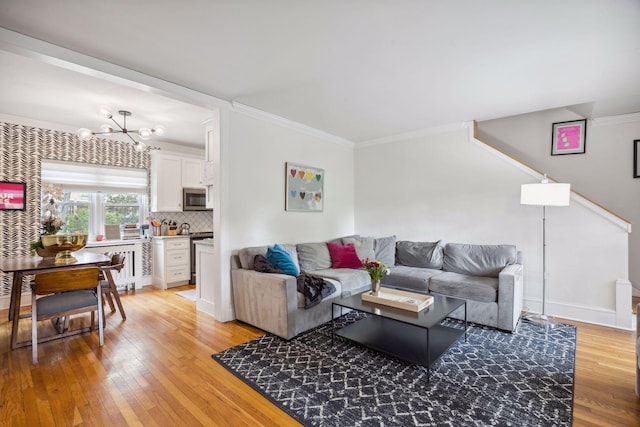 living room with ornamental molding, an inviting chandelier, and light wood-type flooring