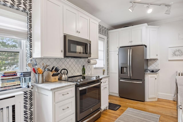 kitchen featuring appliances with stainless steel finishes, light hardwood / wood-style flooring, and white cabinetry