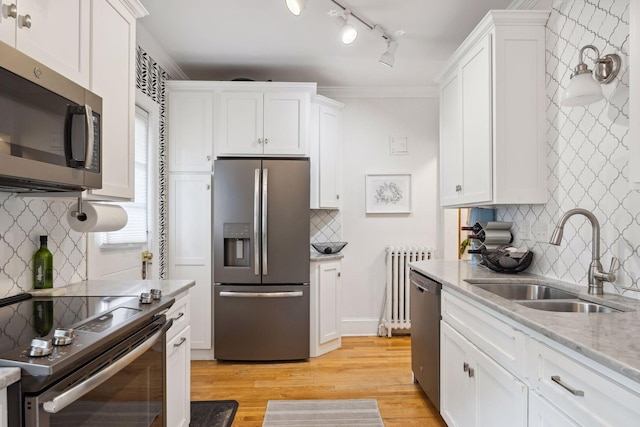 kitchen featuring white cabinets, appliances with stainless steel finishes, light hardwood / wood-style flooring, crown molding, and sink