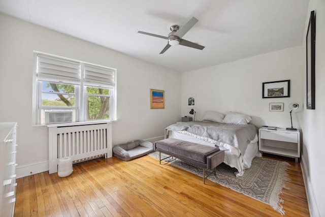 bedroom with ceiling fan, cooling unit, radiator heating unit, and hardwood / wood-style floors