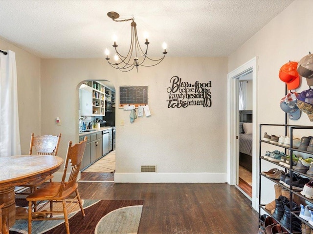 dining space featuring sink, a notable chandelier, hardwood / wood-style flooring, and a textured ceiling