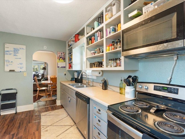 kitchen featuring sink, light hardwood / wood-style flooring, stainless steel appliances, and a textured ceiling