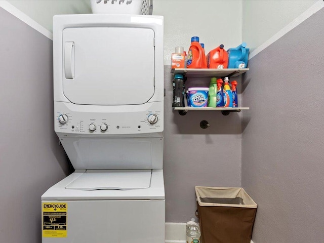 laundry room featuring crown molding and stacked washer and clothes dryer