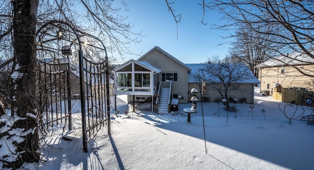 snow covered rear of property with a sunroom