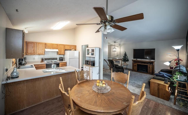 dining space with ceiling fan, sink, dark wood-type flooring, and vaulted ceiling