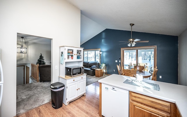 kitchen with light wood-type flooring, ceiling fan with notable chandelier, white dishwasher, decorative light fixtures, and white cabinetry