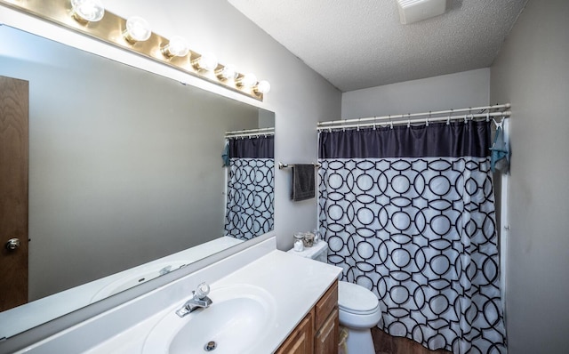 bathroom with hardwood / wood-style floors, vanity, toilet, a textured ceiling, and walk in shower