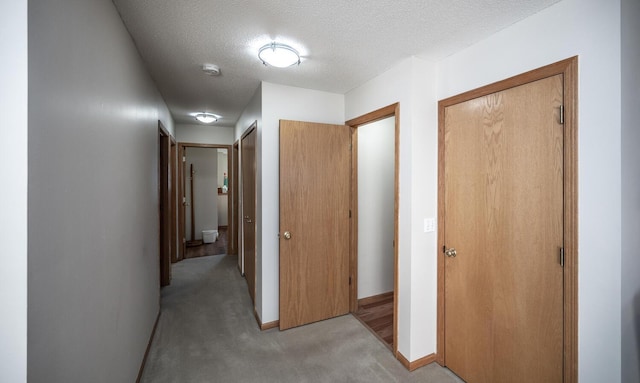 corridor with light carpet and a textured ceiling